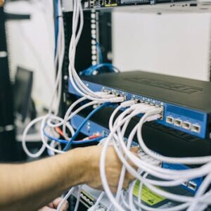 An IT professional configuring network cables in a server rack, focusing on Ethernet connections.